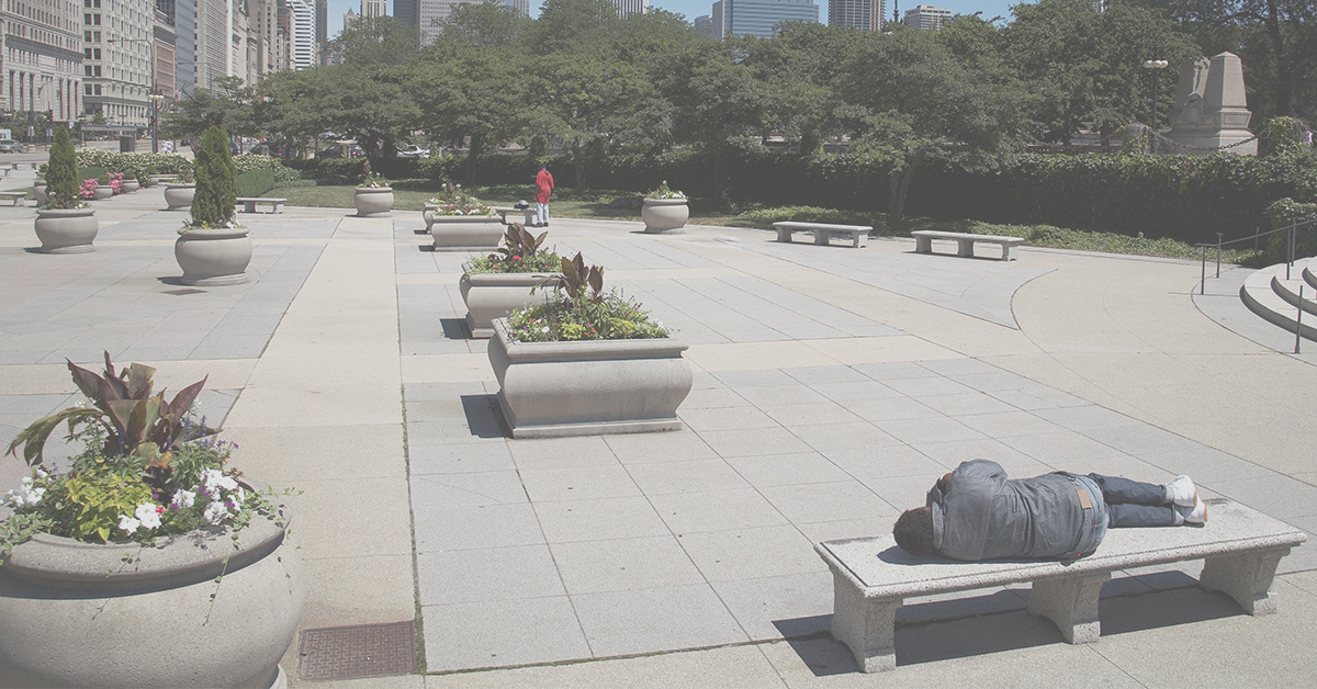 Man sleeping on a bench in a pristine downtown public park in Chicago.