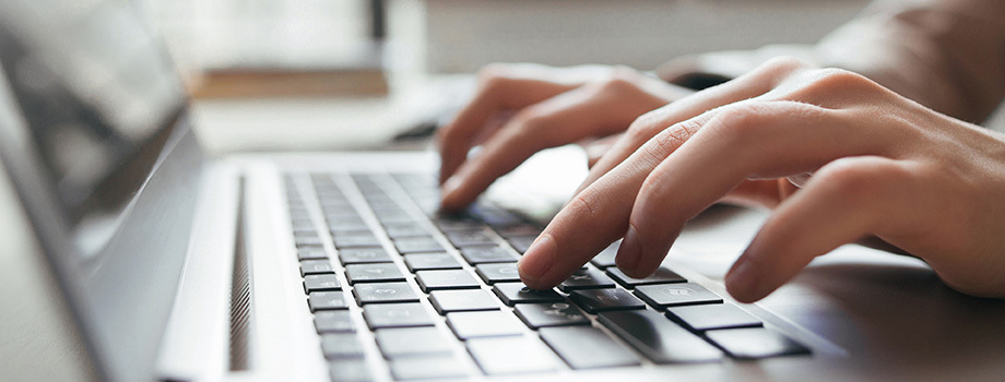 Hands typing on a computer keyboard.