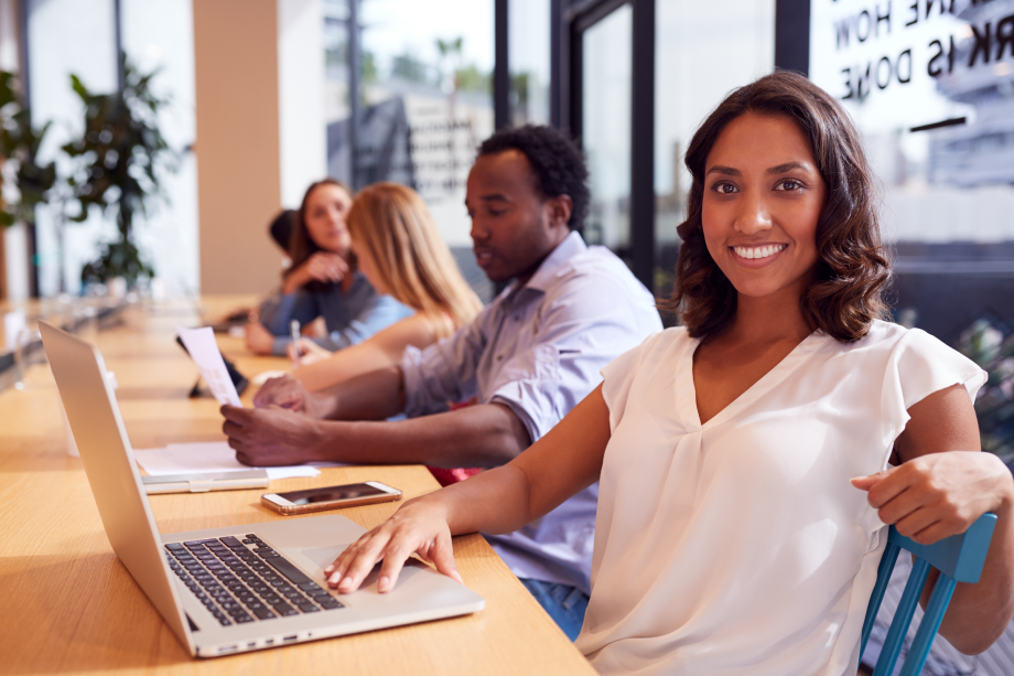 Woman in front of row of students in classroom on her computer.