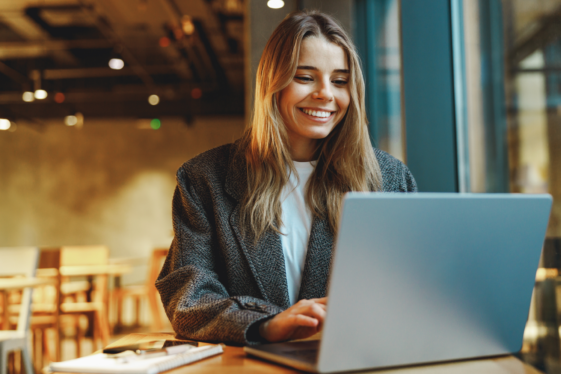 Woman in a blazer smiles at her computer in the office.