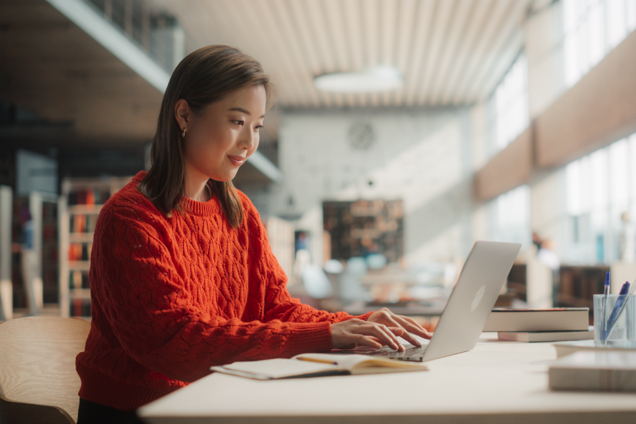 Woman in a red sweater works on her computer in the office.
