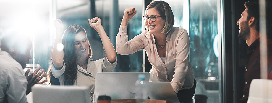 Woman meeting with coworkers in a nonprofit setting raises her hands in celebration.