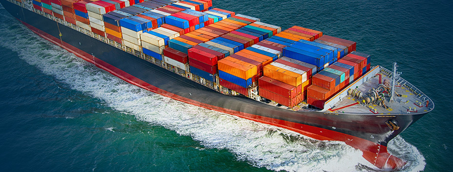 Cargo ship with stacked multi-color containers on deck moving over water.