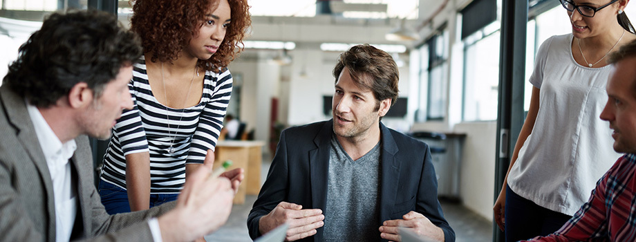 A group of diverse business people debate strategy in a meeting.