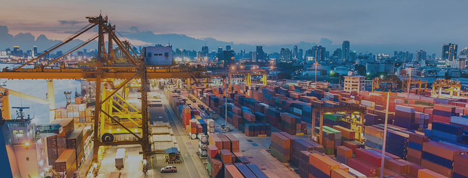 Ship, crane, and shipping containers at dusk.