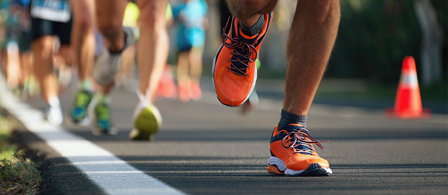 Ground-level view of runners shoes and legs during a marathon representing types of running.