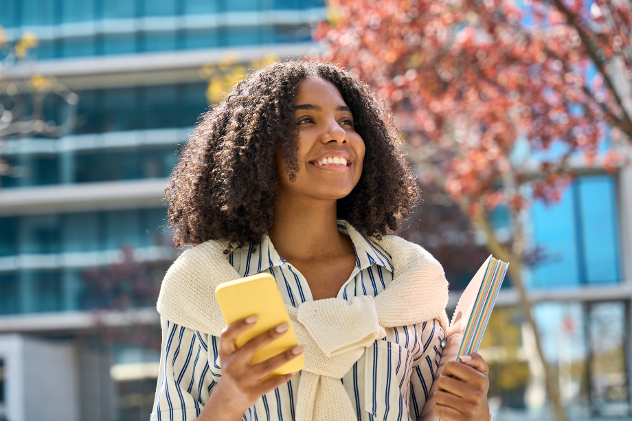 Woman Walks Outside Holding a Yellow Mobile